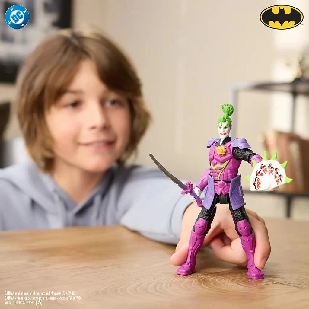 Child playing with DC Comics Ninja Strike The Joker 6-inch action figure, posed with sword and shield, dressed in purple armor with green hair in home setting.