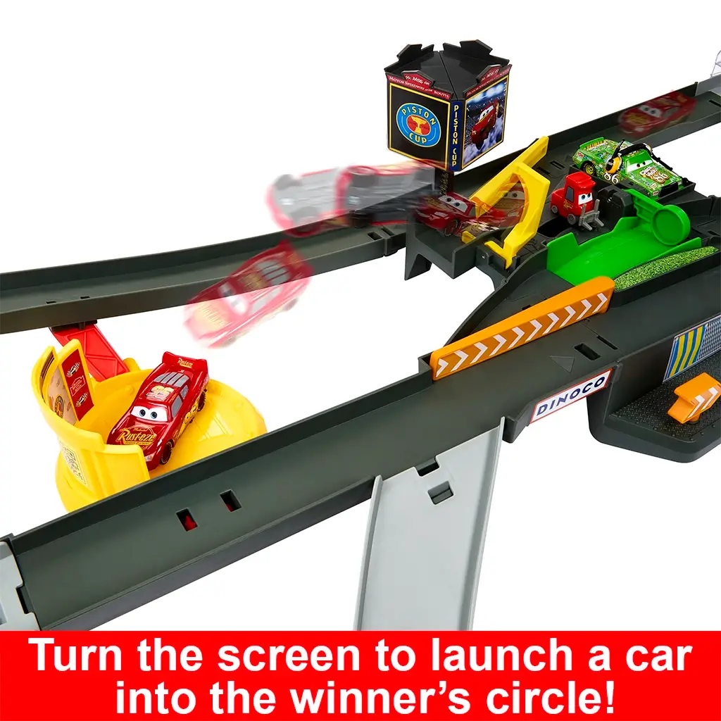 Disney Pixar Cars race track showing dark gray plastic lanes, yellow launch ramp, and red Lightning McQueen car mid-motion, demonstrating the launcher function that sends vehicles into the Piston Cup winner’s circle.