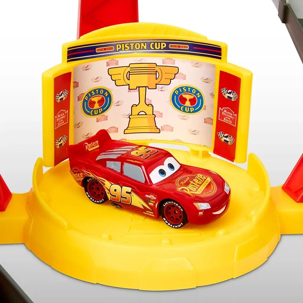 Disney Pixar Cars Lightning McQueen toy vehicle in red plastic with printed decals, number 95, and Rust-eze branding, positioned on a yellow Piston Cup winner’s platform against a clean white background.