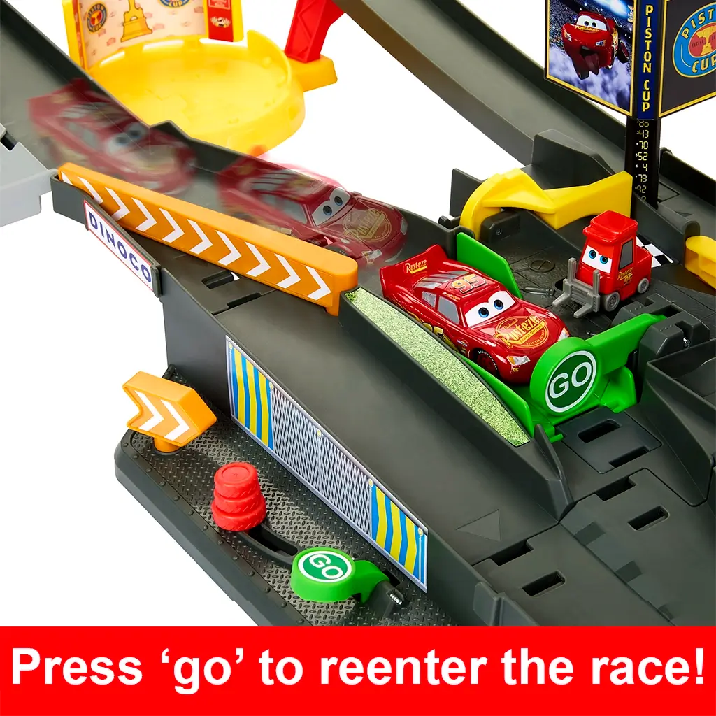 Disney Pixar Cars pit lane detail showing dark gray plastic track, green GO button, yellow barriers, and Lightning McQueen car, illustrating the reentry feature that sends the car back into the Piston Cup race.
