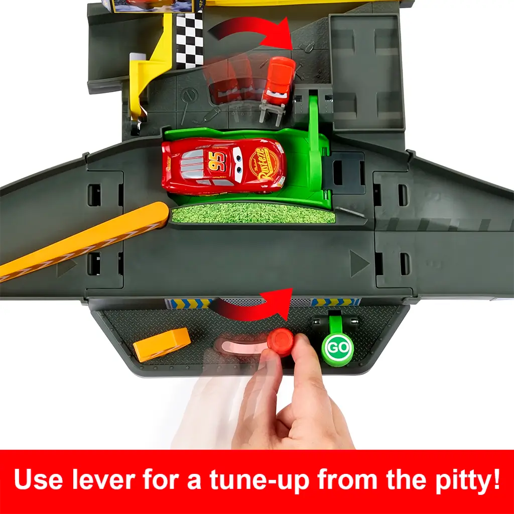 Disney Pixar Cars pit stop section with dark gray molded track, green pit platform, red tune-up lever, and Lightning McQueen car, demonstrating the interactive tune-up feature used during Piston Cup races.
