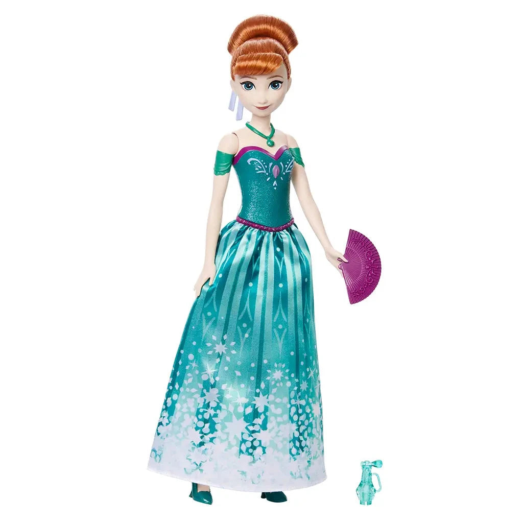 Disney Frozen Anna fashion doll wearing teal off-the-shoulder gown with white snowflake design, holding a purple fan with included accessories nearby.