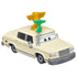 Disney Pixar Cars Brad Winner diecast shown at an angled view, featuring cream-colored glossy metal, squared sedan body, gold winner’s trophy on the roof, green microphone accessory, gray wheels, and calm character expression on white.
