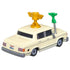 Disney Pixar Cars Brad Winner diecast shown from a rear angled view, highlighting the cream metal body, squared trunk and bumper, gold roof trophy mount, green microphone arm, gray wheels, and classic sedan proportions on white.