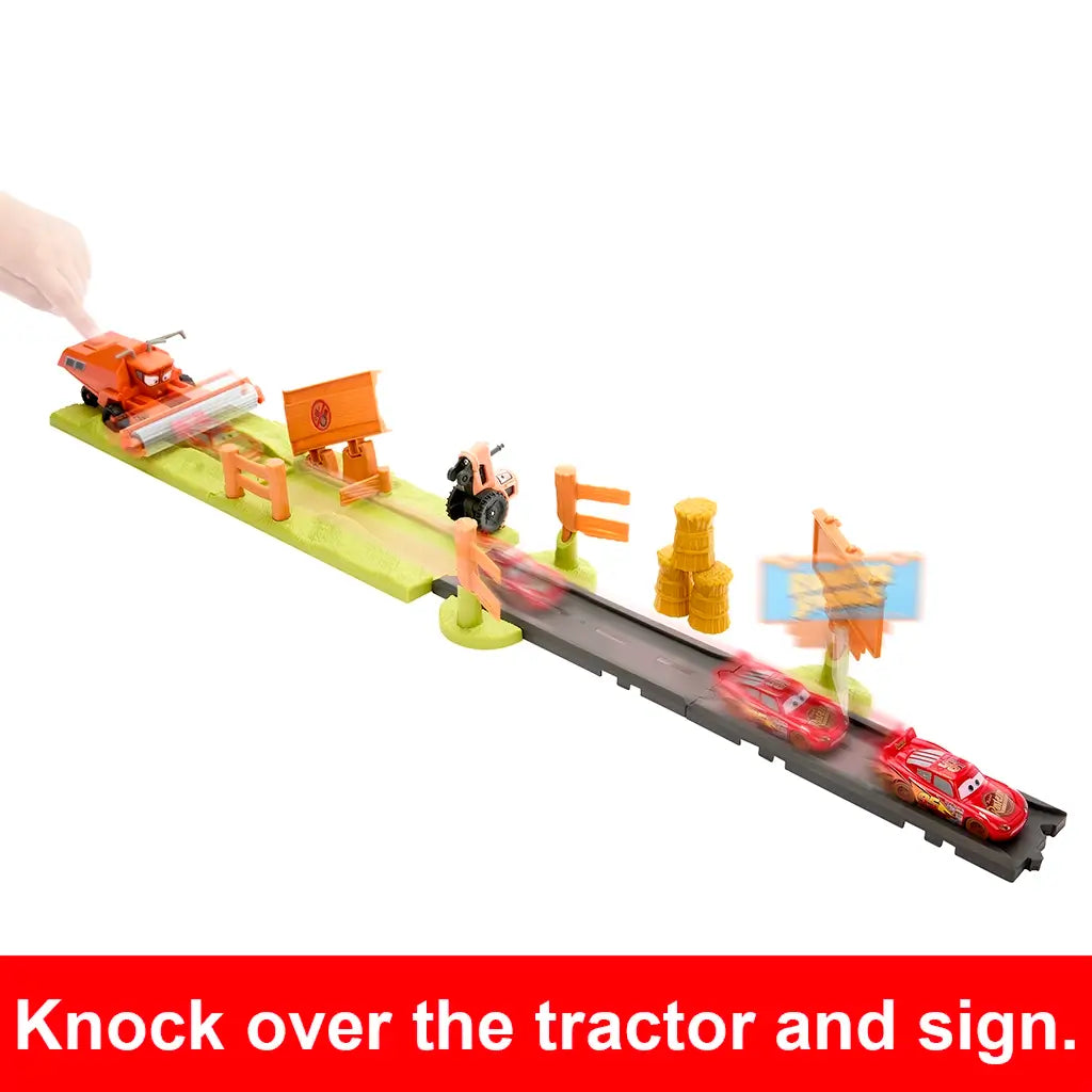 Disney Pixar Cars stunt race toy track with Lightning McQueen racing at high speed, knocking over tractor, hay bales, and Radiator Springs sign during escape challenge.