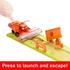 Disney Pixar Cars playset close-up with child pressing orange Frank harvester to launch Lightning McQueen down green ramp, passing wooden fences and sign obstacles.