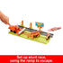Disney Pixar Cars stunt race playset with colorful ramp, roadway, and Radiator Springs sign, featuring Lightning McQueen launched forward past orange tractor and hay bale obstacles.