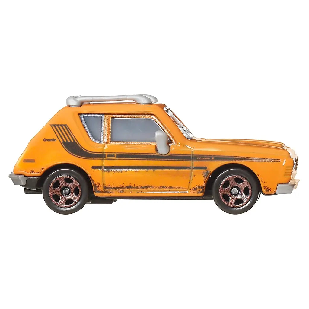 Side profile of Disney Pixar Cars Grem diecast toy, orange body with black stripe detail, rust weathering, silver mirrors, roof rack, and chrome-accented wheels against white background.