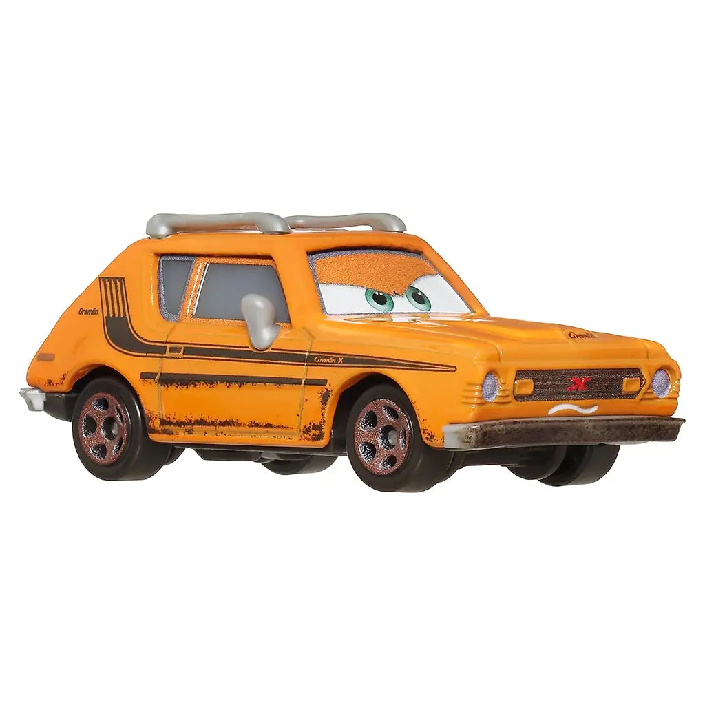 Orange Disney Pixar Cars Grem diecast car with green eyes, silver roof rack, rust-like weathering, and five-spoke wheels, displayed on a white background in a front angled view.