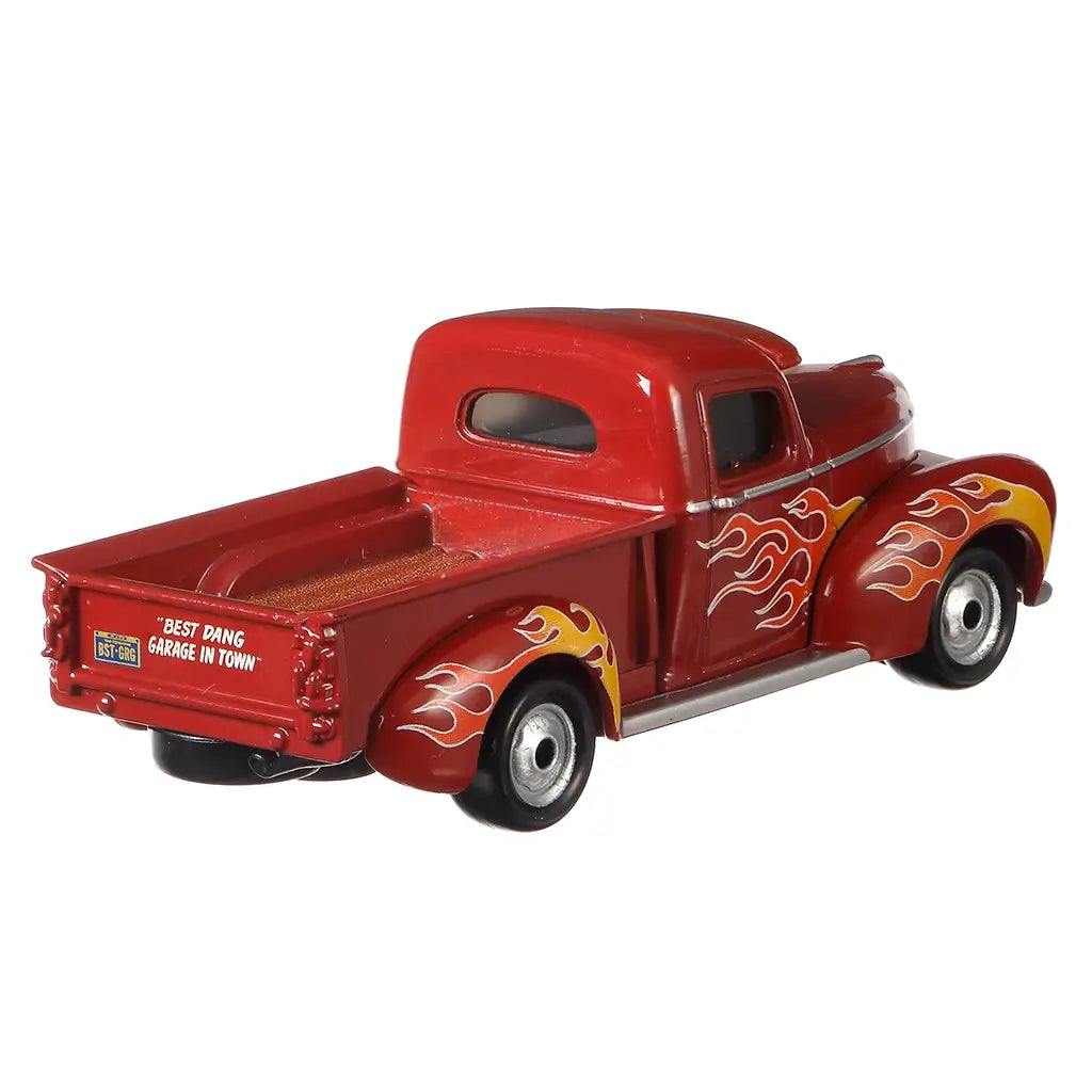 Disney Pixar Cars Heyday Smokey diecast pickup shown from a rear angled view, featuring deep red metal body, open truck bed with textured floor, silver rear bumper, flame graphics on the fenders, and classic proportions on a white studio background.