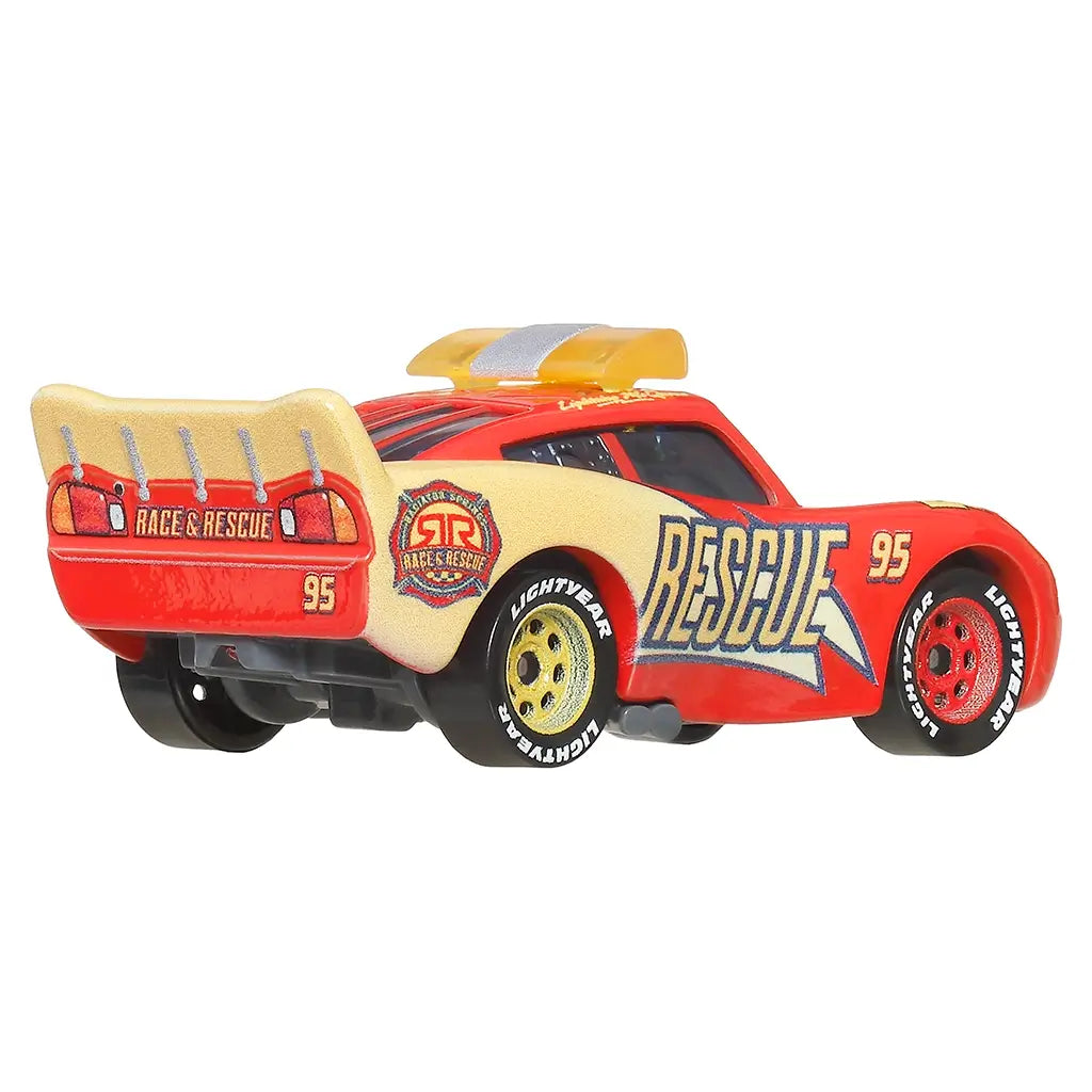 Rescue Lightning McQueen diecast car in red and cream metal with molded spoiler, rounded stock car body, Rescue 95 logos, rear racing details, and Lightyear tires photographed from a rear angled studio view.