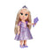 Disney Princess Rapunzel doll in a purple satin-look floral gown, jeweled tiara, and lavender shoes, holding a purple hairbrush beside long blonde hair on white background.