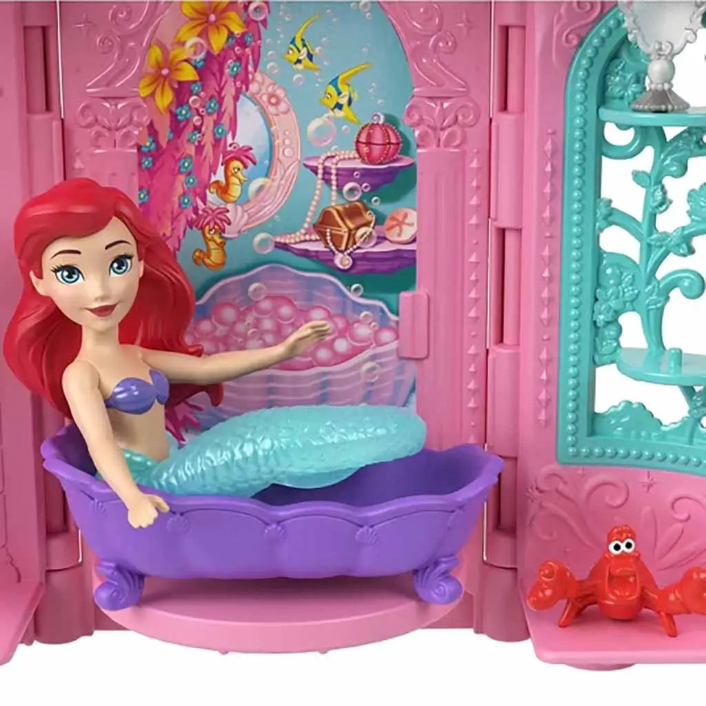 Close-up of Disney Princess Tower Surprise Ariel playset showing The Little Mermaid figure in a purple bathtub with Sebastian crab, colorful undersea background, and ornate pink castle walls.