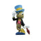 Front view of Jiminy Cricket figure wearing blue hat, black jacket, and red vest, holding umbrella with a smile; Disney Showcase 85th anniversary Pinocchio collectible.