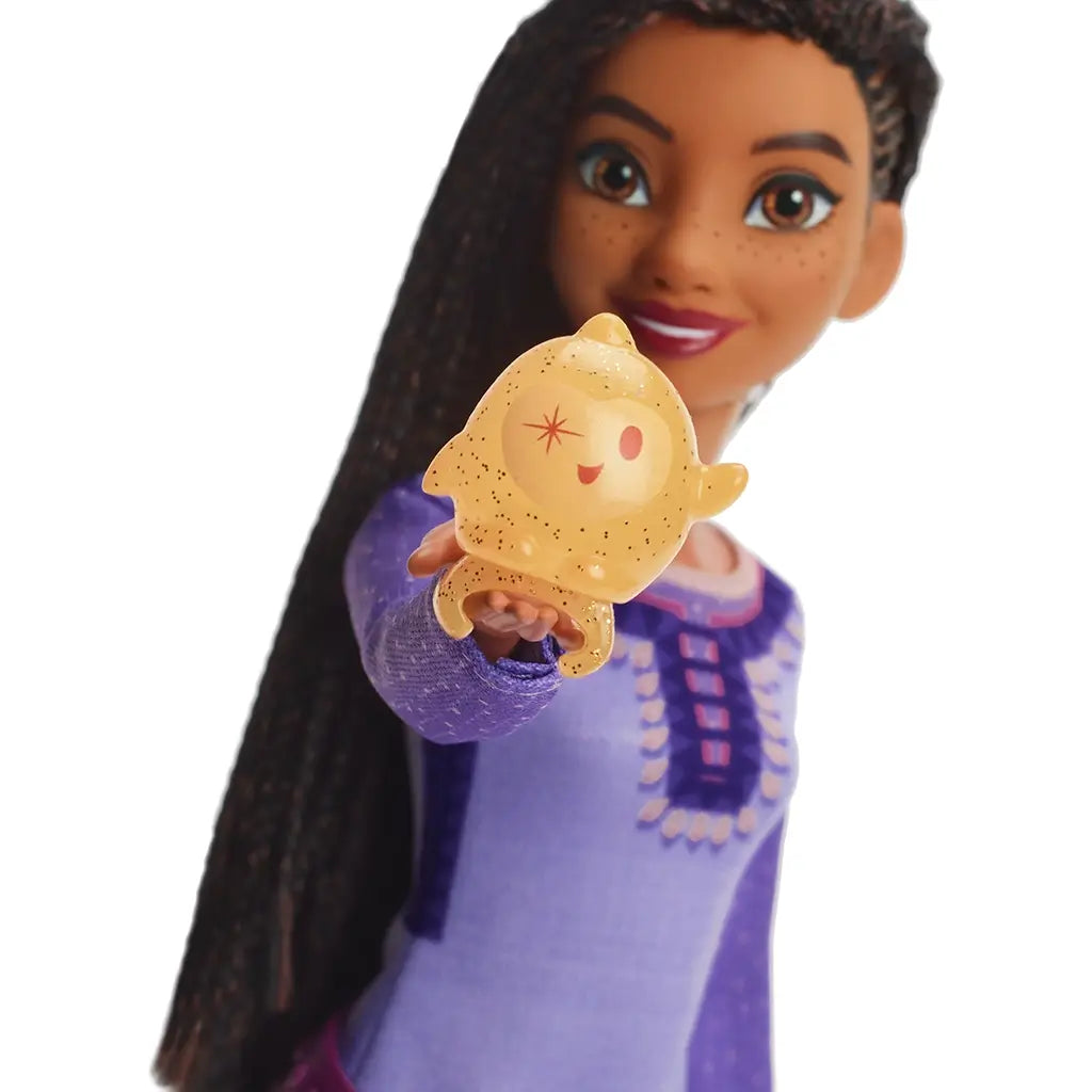 Disney Wish Singing Asha of Rosas doll holding clip-on glittery yellow Star character with a smiling face, showcasing magical accessory attachment to hand.