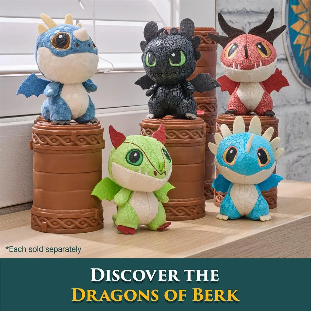 Dragons of Berk mini plush characters in blue, black, red, and green textured fabric with rounded shapes and tiny wings, arranged on brown totem stands near a bright window display.