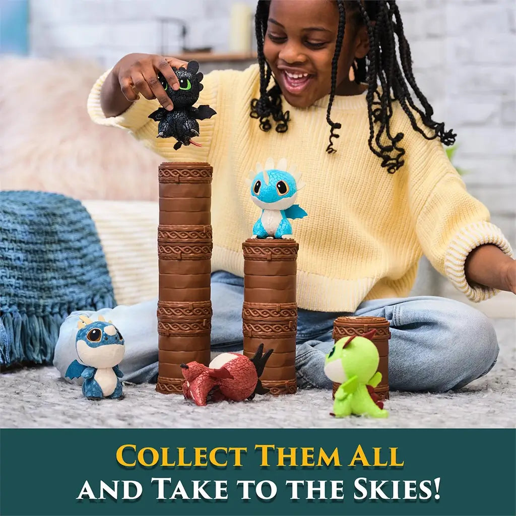 How to Train Your Dragon mini plush toys in bright blue, green, red, and black textured fabric with round bodies and small wings, stacked on brown totem capsules in a cozy living room play scene.