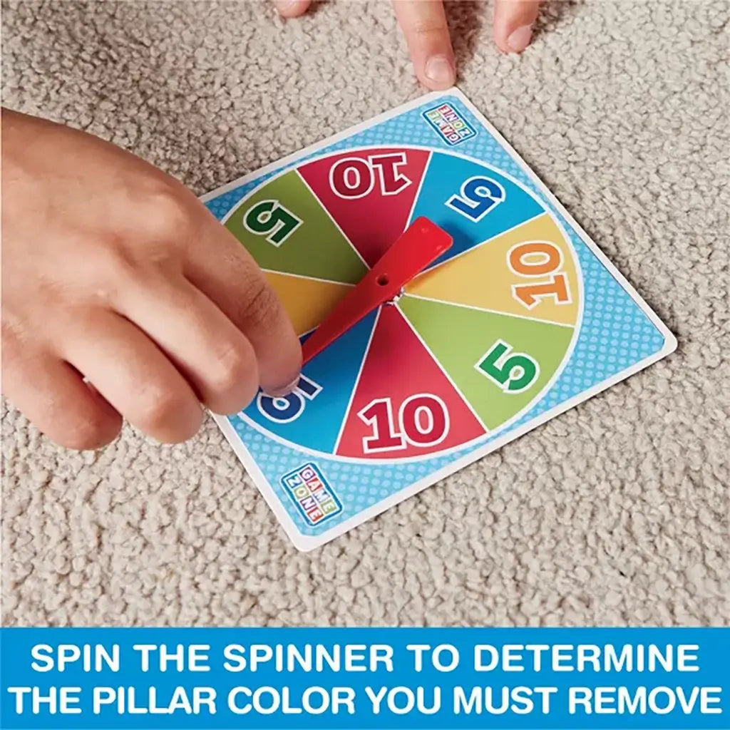 Child’s hand spinning colorful cardboard game spinner with red pointer, used to select the pillar color for removing pieces in the Tumbling Tower stacking challenge.