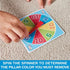 Child’s hand spinning colorful cardboard game spinner with red pointer, used to select the pillar color for removing pieces in the Tumbling Tower stacking challenge.