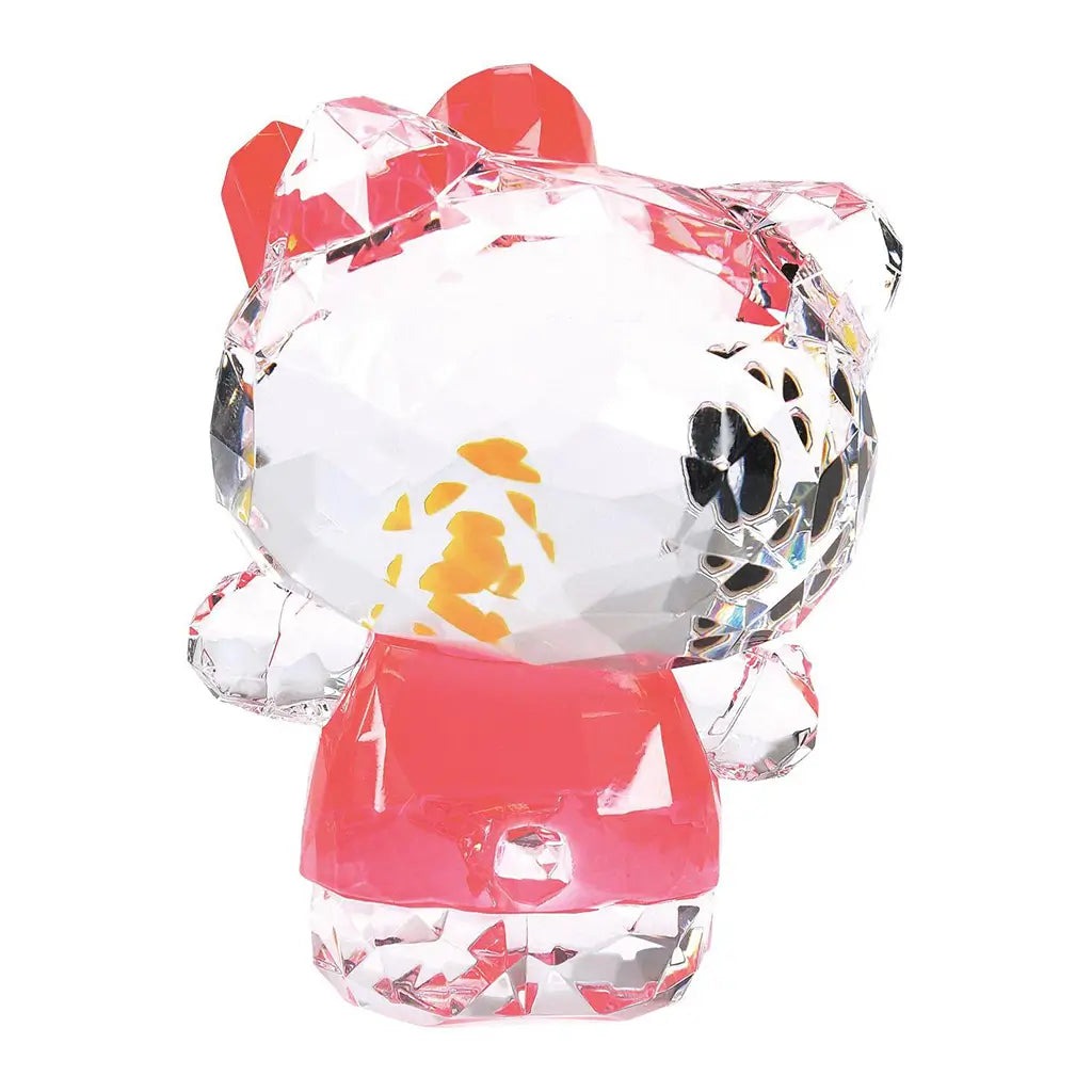 Back view of faceted Hello Kitty figurine in clear acrylic with red bow and pink dress, showing tail and fine etched details.