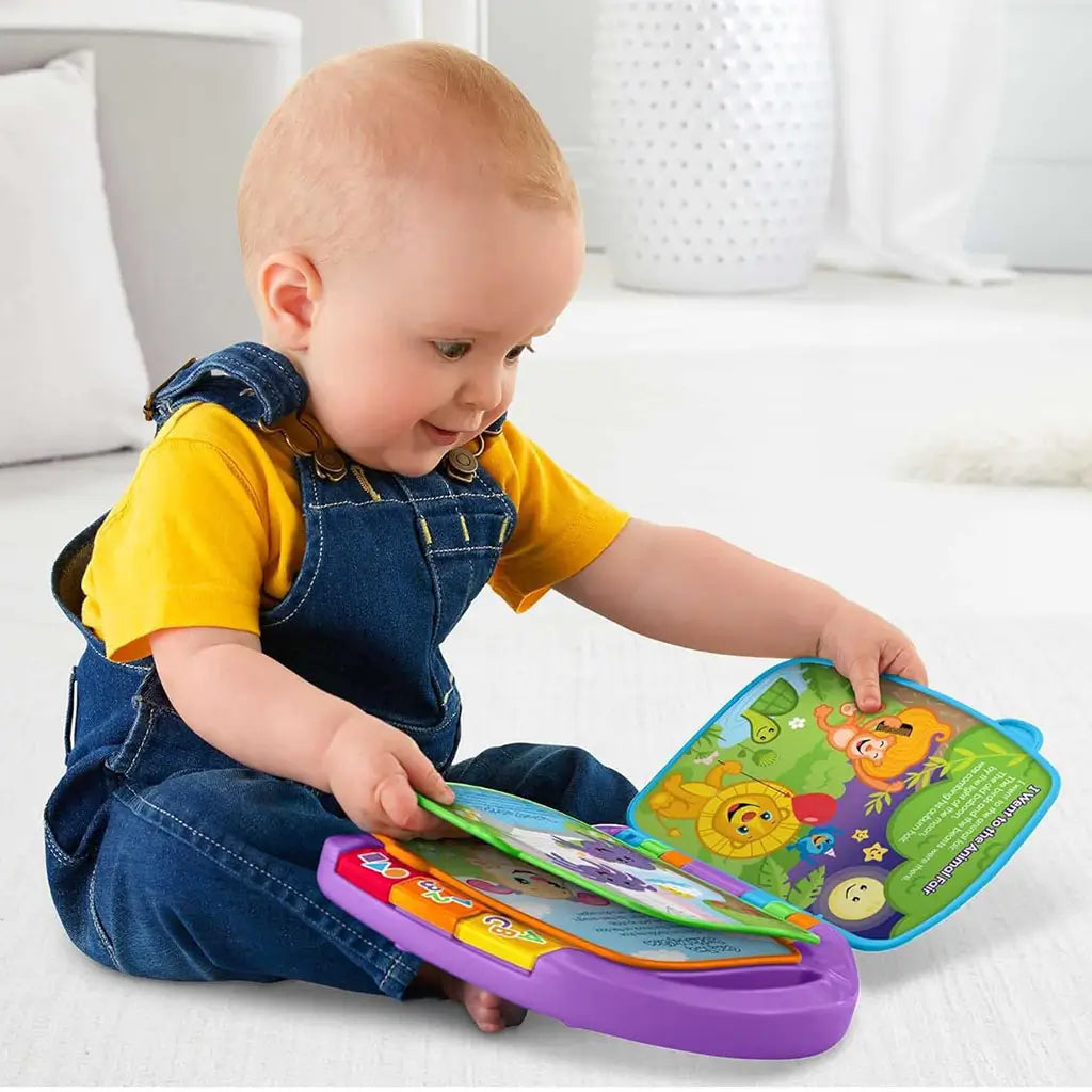 A baby in denim overalls plays with the Fisher-Price Storybook Rhymes toy, turning colorful plastic pages that display friendly animal illustrations in a bright, soft-lit home setting.