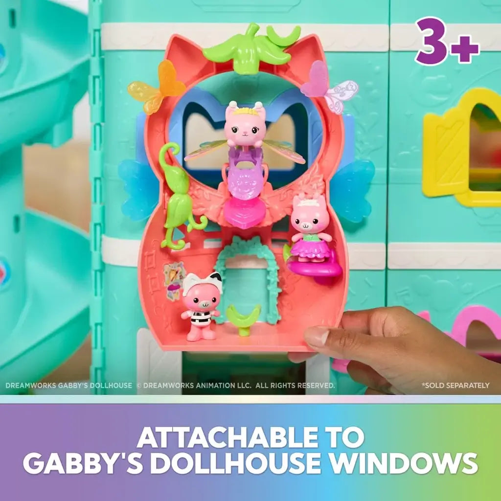 Gabby's Dollhouse attachable fairy playset in coral and mint plastic clipped onto a teal dollhouse window, displaying winged cat figures on molded shelves and arches.