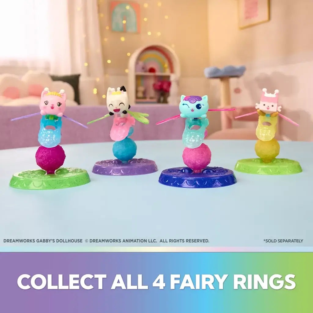 Gabby's Dollhouse fairy ring collectibles in colorful plastic with four winged cat figures balanced on glittery bases, arranged in a pastel playroom setting for imaginative display.