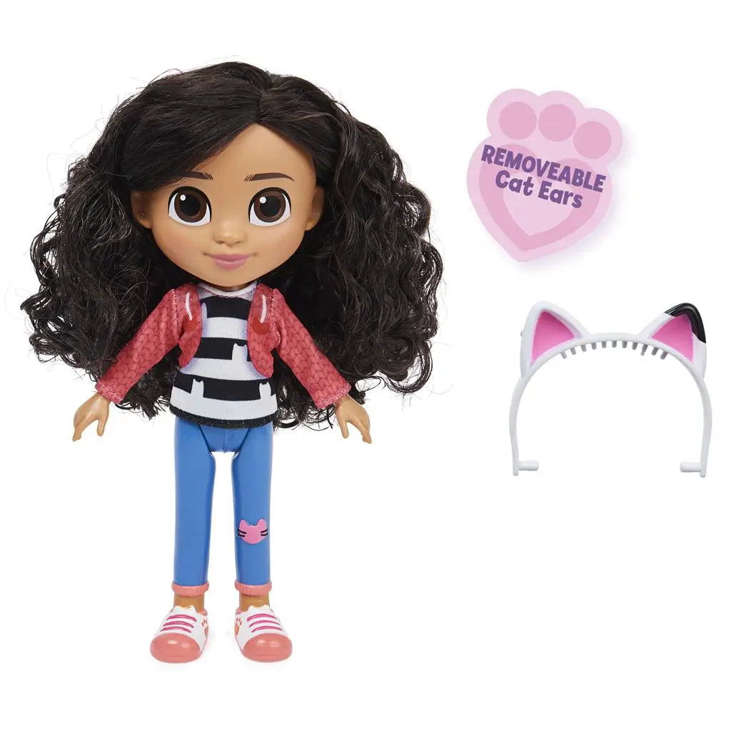Gabby's Dollhouse Gabby Girl doll with removable white and pink cat-ear headband, molded plastic figure in pink jacket and blue jeans displayed beside accessory on a plain white background.