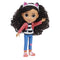 Gabby's Dollhouse Gabby Girl doll wearing textured pink jacket, striped top, and blue jeans, smooth plastic fashion figure with large brown eyes and full curly hair, waving against a white studio background.
