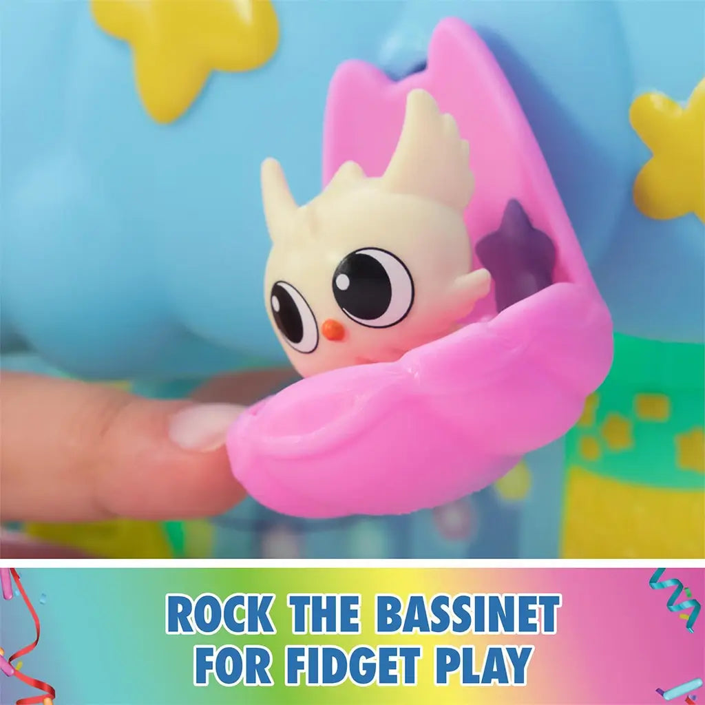 DreamWorks Gabby's Dollhouse Kitty Care Ear Purrfect Playroom pink rocking bassinet in smooth plastic cradling baby kitten figure against blue cloud backdrop for sensory fidget play.