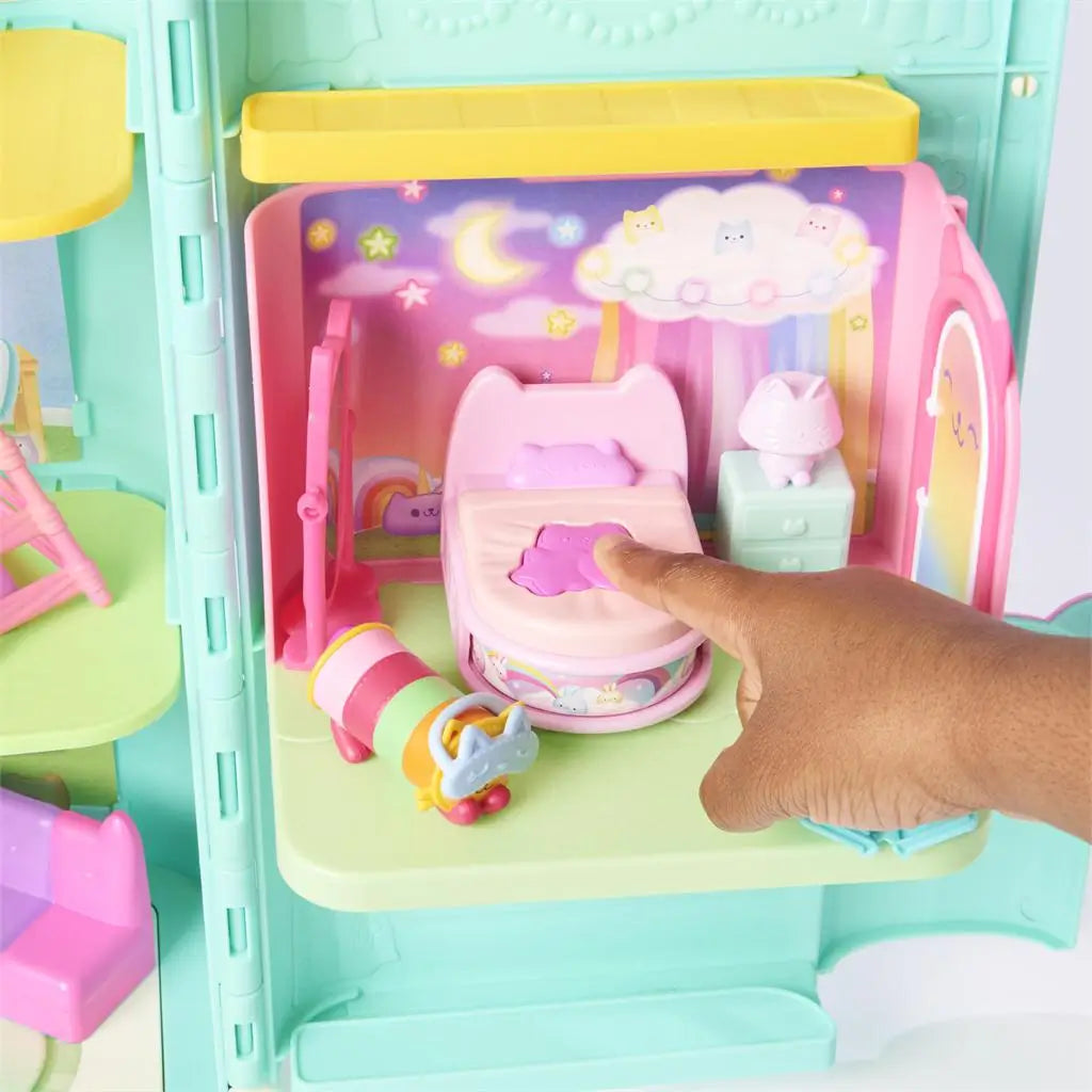 Gabby’s Dollhouse transforming bed feature in pastel pink plastic with rounded shape and soft details, small figure interacting with bed in cozy room scene, demonstrating play function on white background.