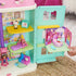Gabby’s Dollhouse compatible playset in pastel plastic with fold-out room structure and small furniture pieces, detailed interior scenes with shelves and bed, displayed open on a textured floor background.