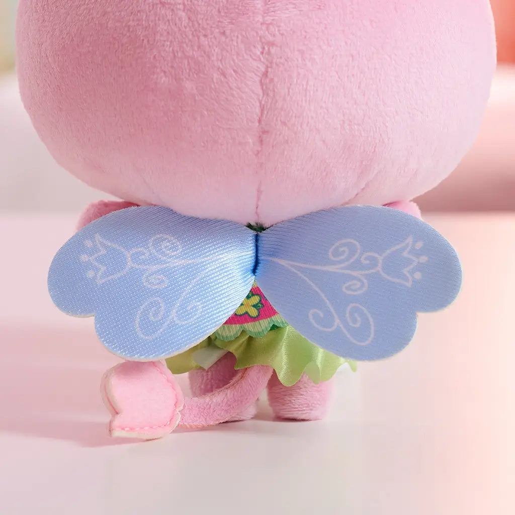 Gabby's Dollhouse Cakey Cat plush toy in pink plush fabric, small rounded kitten shape with stitched features, shown from back with light blue fairy wings detail, highlighting decorative costume design.
