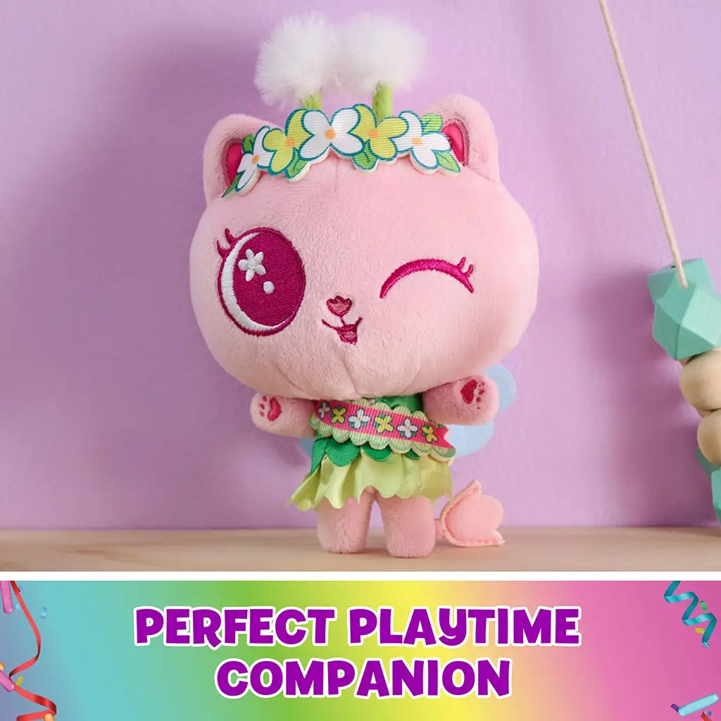 Gabby's Dollhouse Cakey Cat plush toy in pink and green fabric, rounded kitten shape with floral crown and wings, displayed on a table in a pastel room, emphasizing imaginative playtime companion.