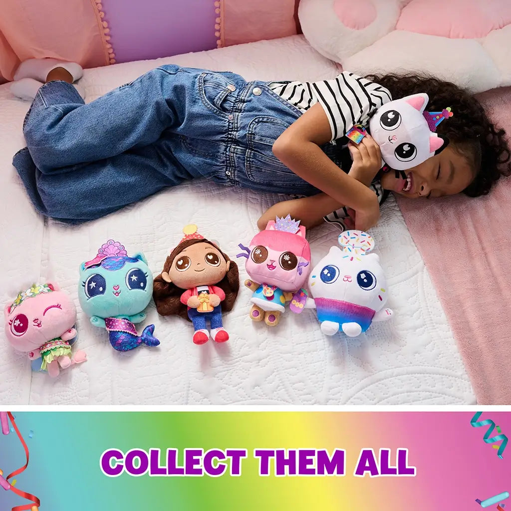 Gabby's Dollhouse plush toys in bright multicolor fabric, small rounded character shapes with embroidered faces, arranged beside a smiling child on a bed, showcasing collectible variety and playful theme.