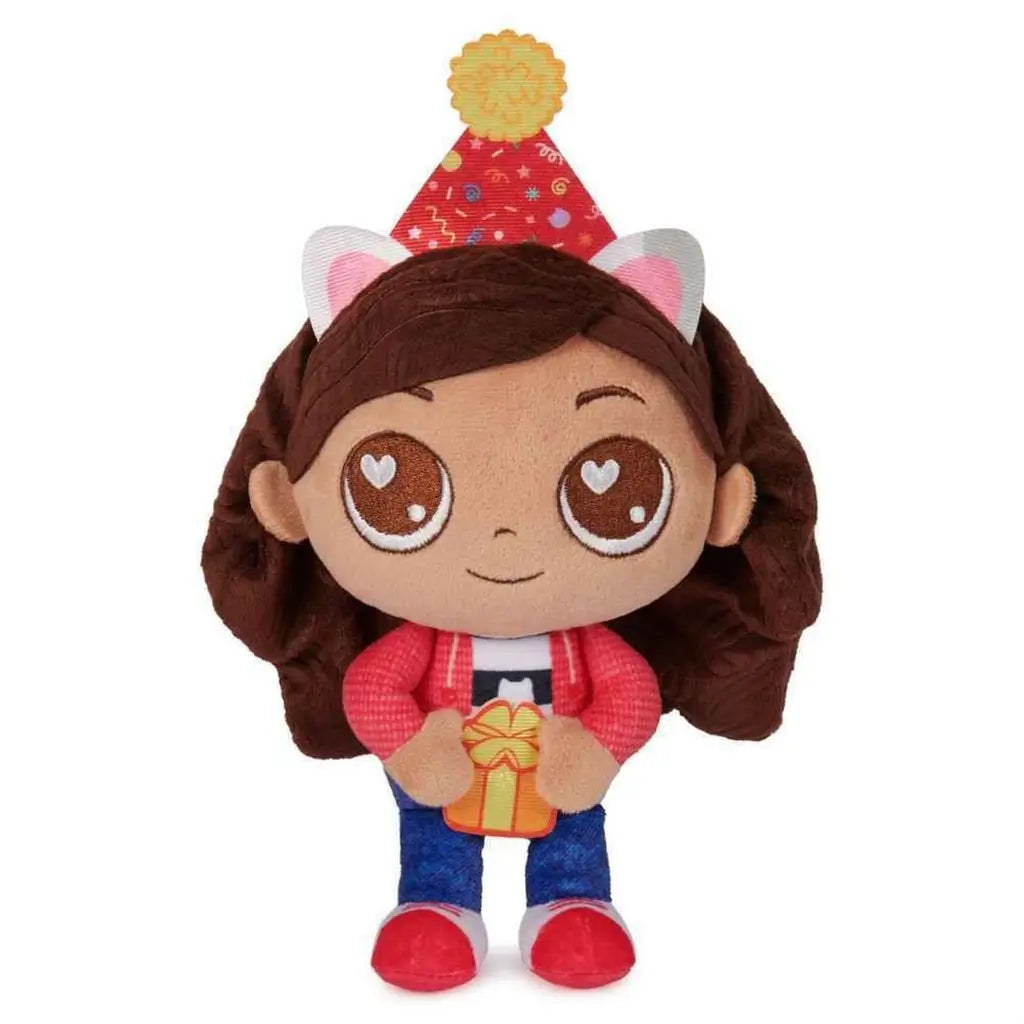 Gabby’s Dollhouse Gabby Girl plush toy in brown, red, and blue soft fabric with large embroidered eyes, cat ear headband, and party hat holding a gift designed as a cuddly character figure on a clean white background.