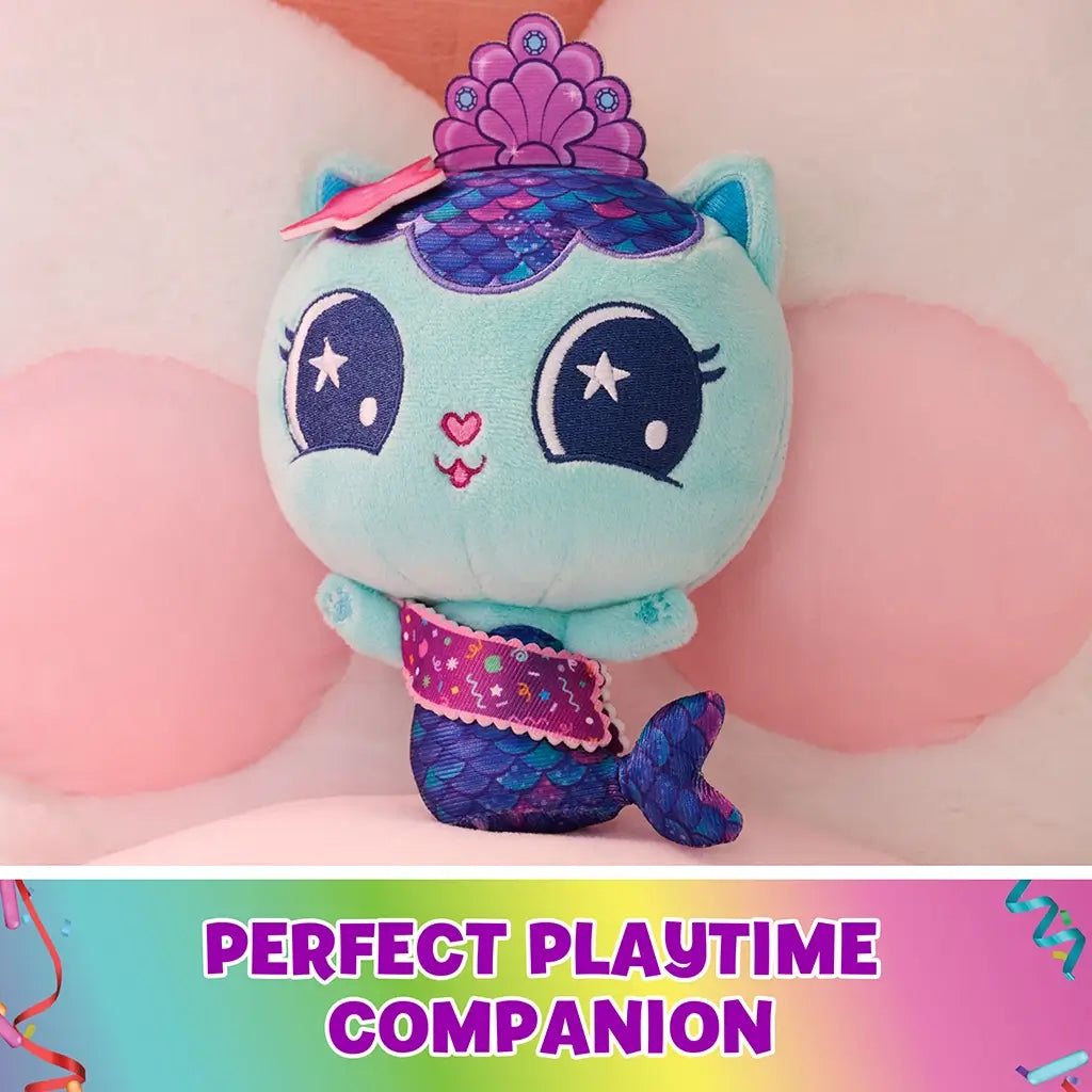 teal plush mermaid cat toy Gabby's Dollhouse, soft fuzzy texture with purple scaled tail and crown detail, rounded cuddly shape resting on pillows in a pastel bedroom setting for playtime display