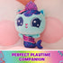 teal plush mermaid cat toy Gabby's Dollhouse, soft fuzzy texture with purple scaled tail and crown detail, rounded cuddly shape resting on pillows in a pastel bedroom setting for playtime display