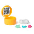 Gabby's Dollhouse surprise accessory capsule in glossy yellow plastic with hinged lid showing QR code inside, displayed open beside tiny costume pieces on a white surface.