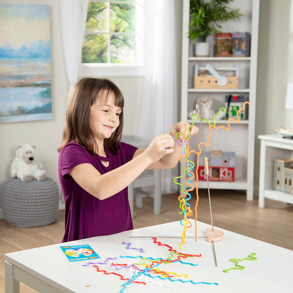 Girl playing a single player variation of the Melissa and Doug Suspend Junior Balance Game