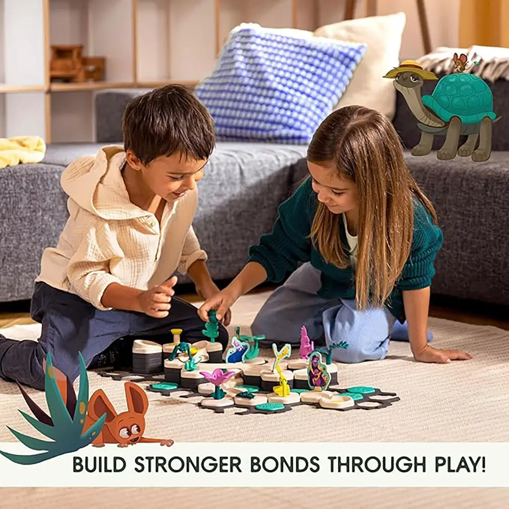 Two children sitting on a beige rug playing with GraviTrax Junior Desert Starter Set, moving colorful desert animal pieces on hexagonal tiles in a living room setting.