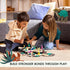 Two children sitting on a beige rug playing with GraviTrax Junior Desert Starter Set, moving colorful desert animal pieces on hexagonal tiles in a living room setting.