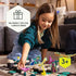 Young girl smiling while arranging pink and green desert-themed figures on GraviTrax Junior tiles, with banner noting the set as a perfect gift for curious kids ages three and up.