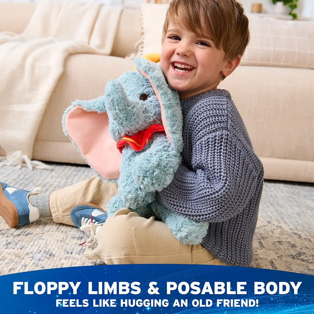 Disney Dumbo plush toy in soft blue with flexible plush body, floppy limbs, oversized pink ears, yellow hat, and red clown collar, posed to demonstrate gentle flexibility and huggable comfort for toddlers and collectors alike.