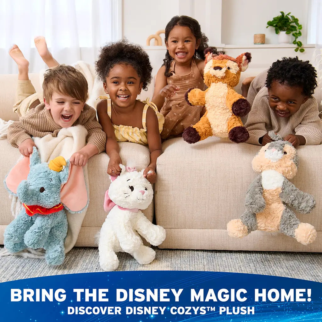 Disney plush collection featuring white, gray, and pastel animal toys with soft high-pile textures, rounded cuddly forms, designed for toddlers and kids, displayed together on a sofa in a bright family living space.