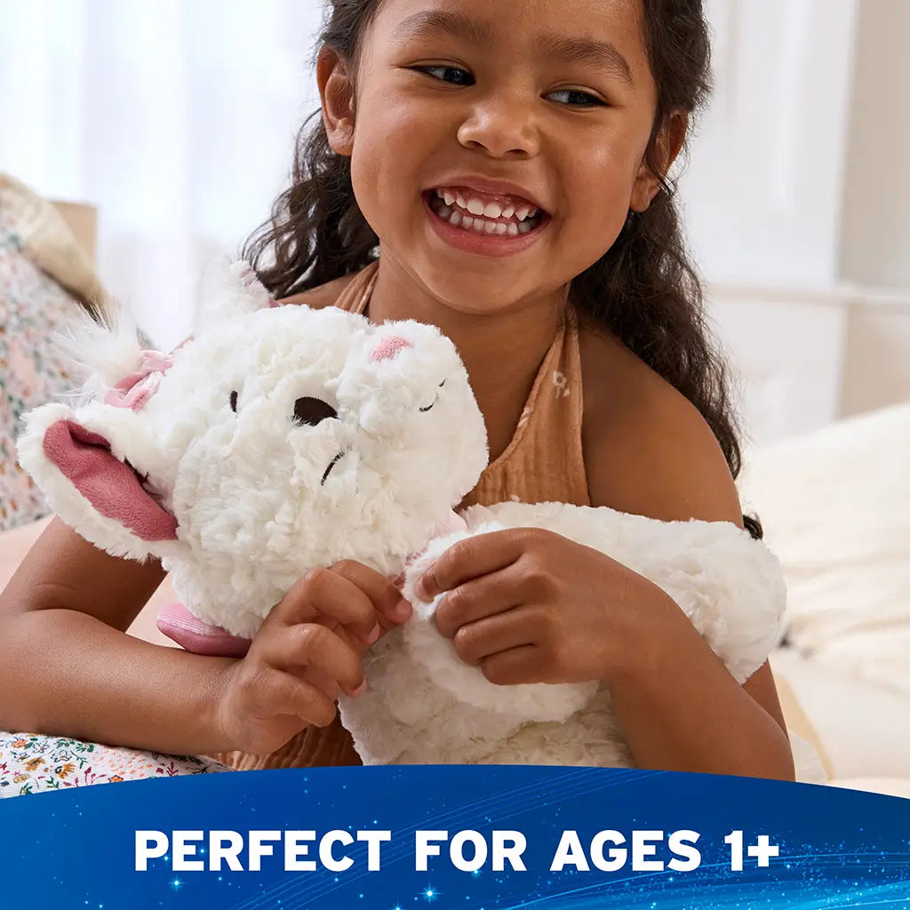 Disney plush toy in white with a soft fluffy texture and pink velour accents, rounded kitten form, designed for comforting play, shown being hugged by a smiling child indoors in a bright, cozy bedroom setting.