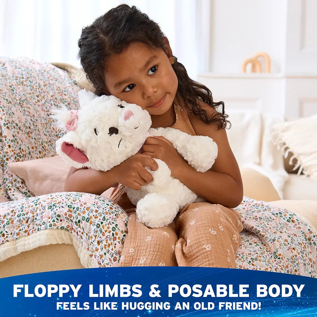 Disney plush toy in white with soft fluffy texture, pink velour ears and bow, rounded kitten body with floppy limbs, designed to be posable and huggable, shown being cuddled by a child in a softly lit bedroom setting.
