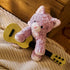GUND Cozys Kitten plush kitten in lavender fuzzy fabric with a soft rounded body, posed holding a small toy guitar on a woven rug to suggest imaginative play, creativity, and playful nursery storytelling scenes.