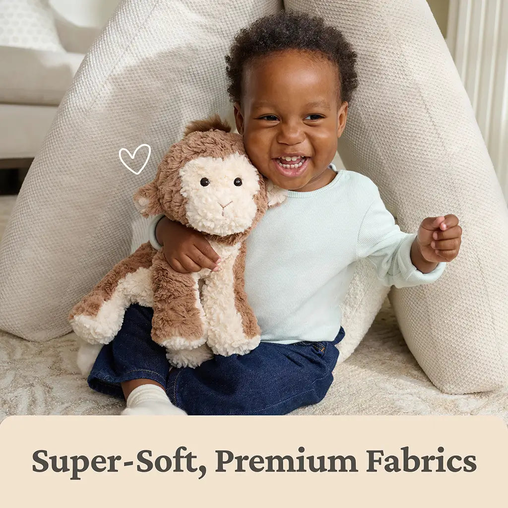 GUND Cozys monkey stuffed animal made from super-soft premium brown and cream plush fabrics with a fuzzy texture and relaxed rounded body, shown cuddled by a smiling baby to emphasize comfort, safety, and everyday companionship.