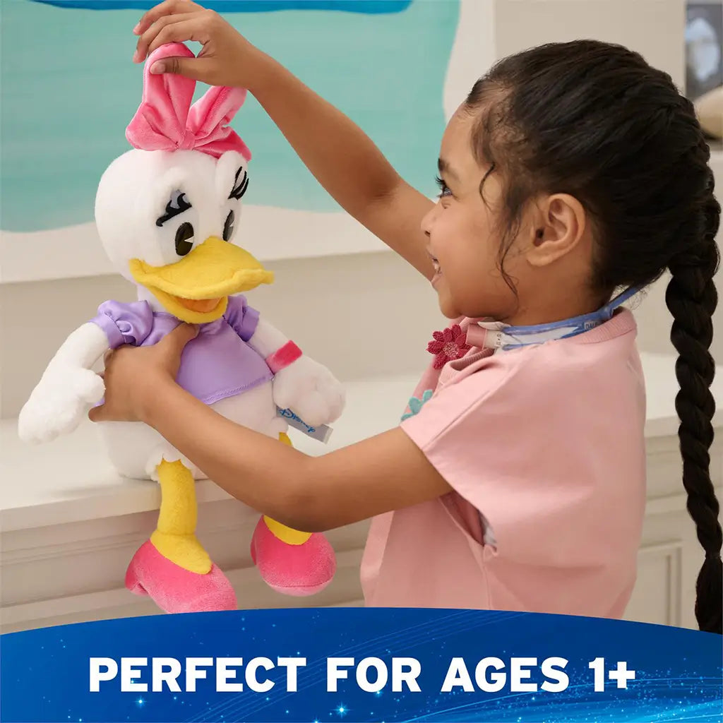 Disney Daisy Duck plush shown in lifestyle scene with a child holding the toy, featuring soft white plush fabric, pink bow and shoes, lavender shirt, and friendly character expression for imaginative play.